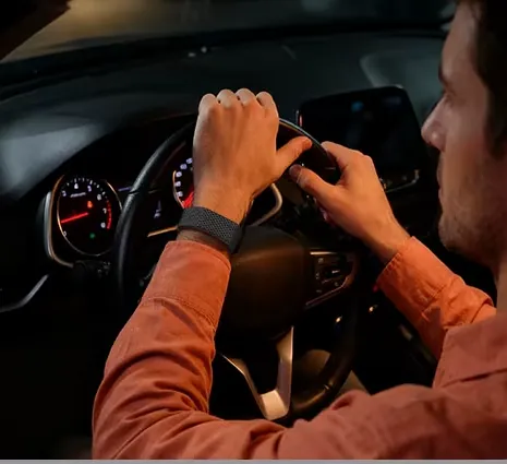 A driver taps the band on his wrist at the wheel at night